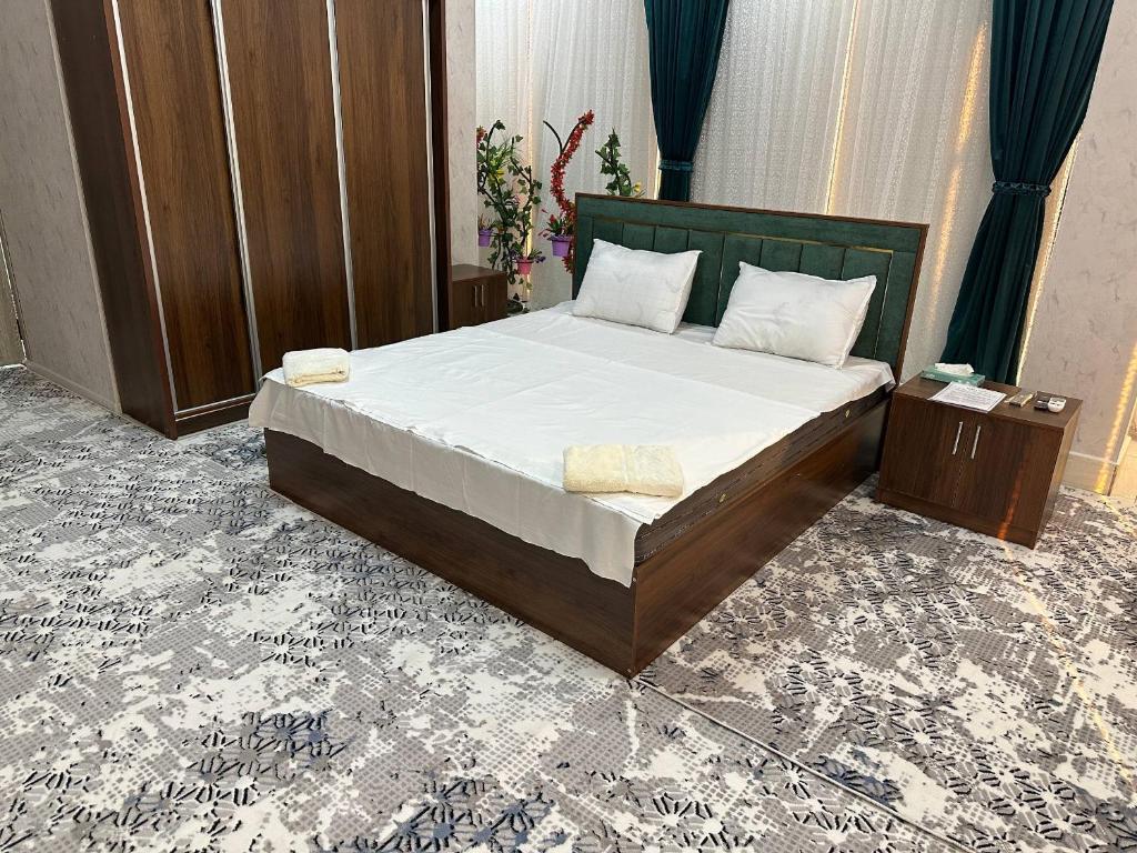 une chambre avec un grand lit avec des draps blancs dans l'établissement Rubin Hotel, à Navoï