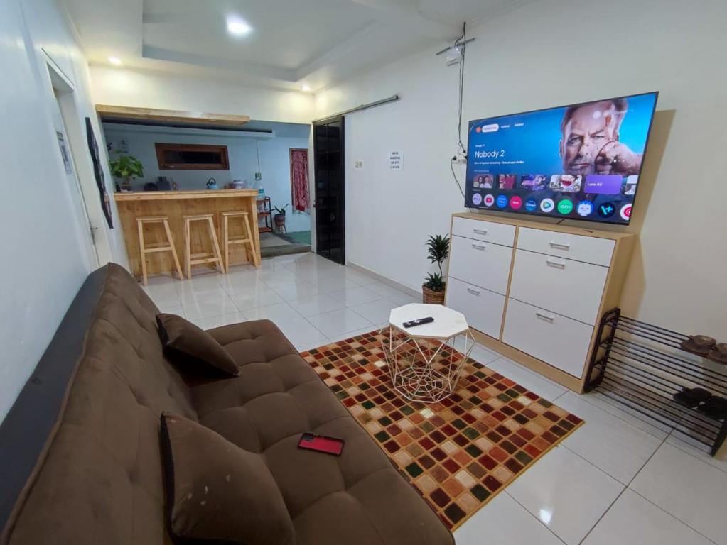 een woonkamer met een bank en een flatscreen-tv bij Erigeron homestay dieng in Banjarnegara