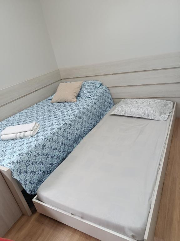 two beds in a small room with at Lar doce lar, Quarto solteiro Bicama, residência Familiar Compartilhada in Pato Branco