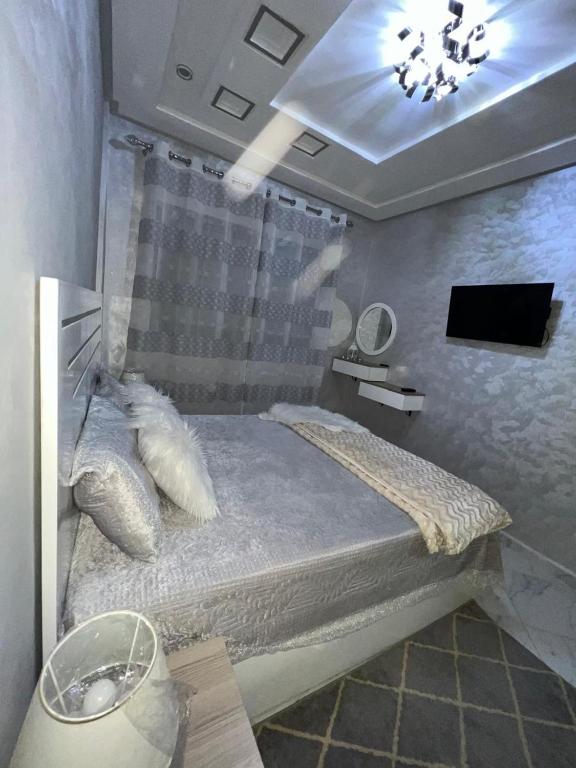 een slaapkamer met een bed in een kamer met een tv bij Shahd in Meknès