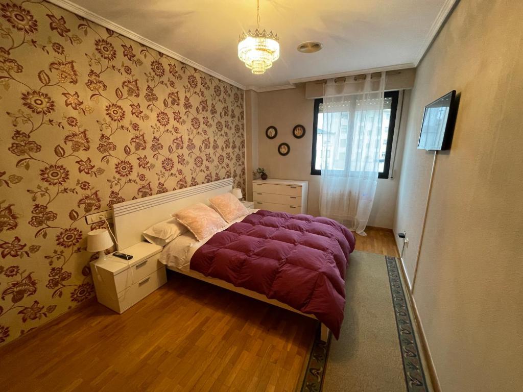 ein Schlafzimmer mit einem Bett mit einer lila Decke in der Unterkunft Bierzo Explore in Ponferrada