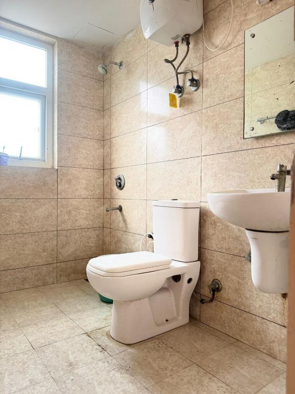 a bathroom with a toilet and a sink at Vrindavan Comfort Stay in Chhatikara