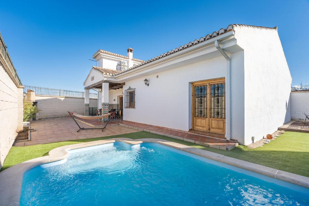 a swimming pool in front of a house at Sueños De La Vega in Las Gabias