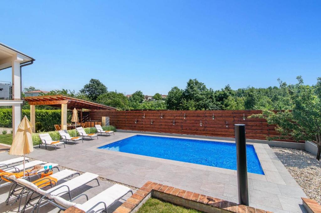einen Pool mit Stühlen und einer Ziegelwand in der Unterkunft Villa Zupan by Villa Plus in Vranići