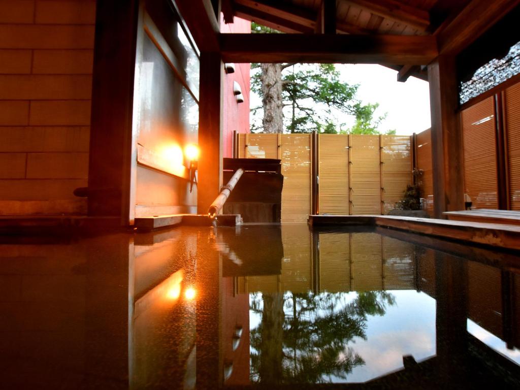 a house with a pool of water in front of it at Okunikko Konishi Hotel in Nikko