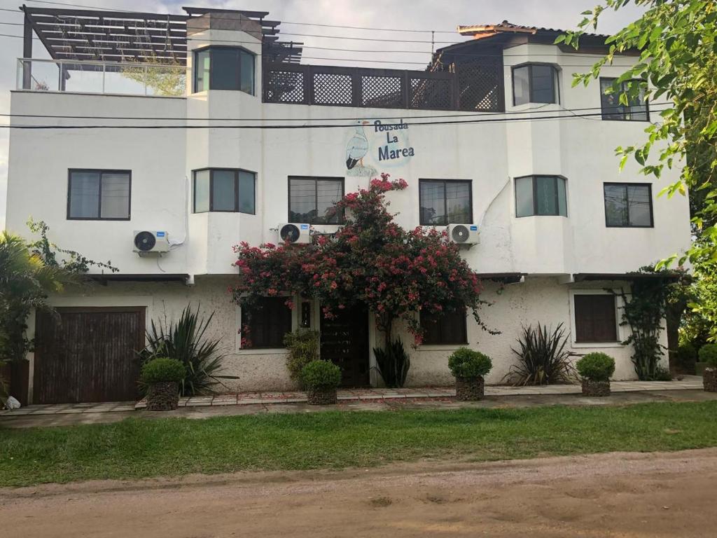 een wit gebouw met een bloeiende boom ervoor bij Pousada La Marea in Rio Grande