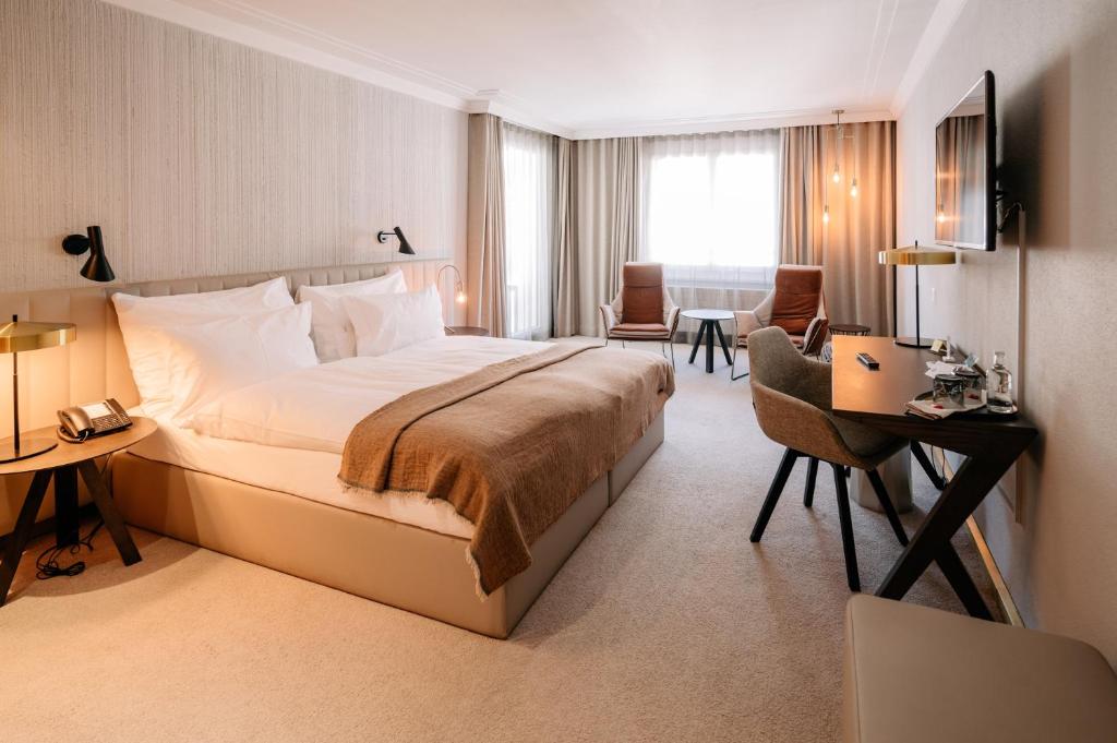 a hotel room with a large bed and a desk at Kongress Hotel Davos in Davos