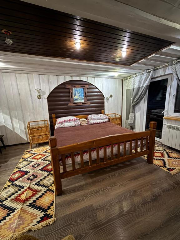 een slaapkamer met een houten bed en een tapijt bij У Віти номер 5 in Synevyrsʼka Polyana