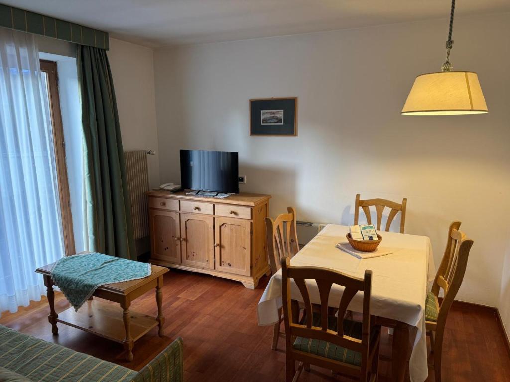 een eetkamer met een tafel en een tv bij Sport Hotel Astoria Residence in La Villa