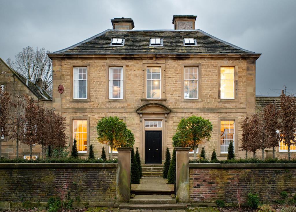 a large brick house with a black door at Wren Place Hall in Barnsley