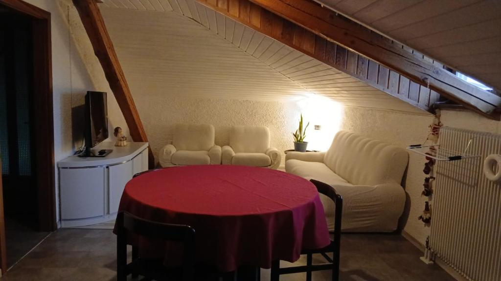 een woonkamer met een rode tafel en een bank bij Ampia Mansarda a Dimaro in Val di Sole in Monclassico