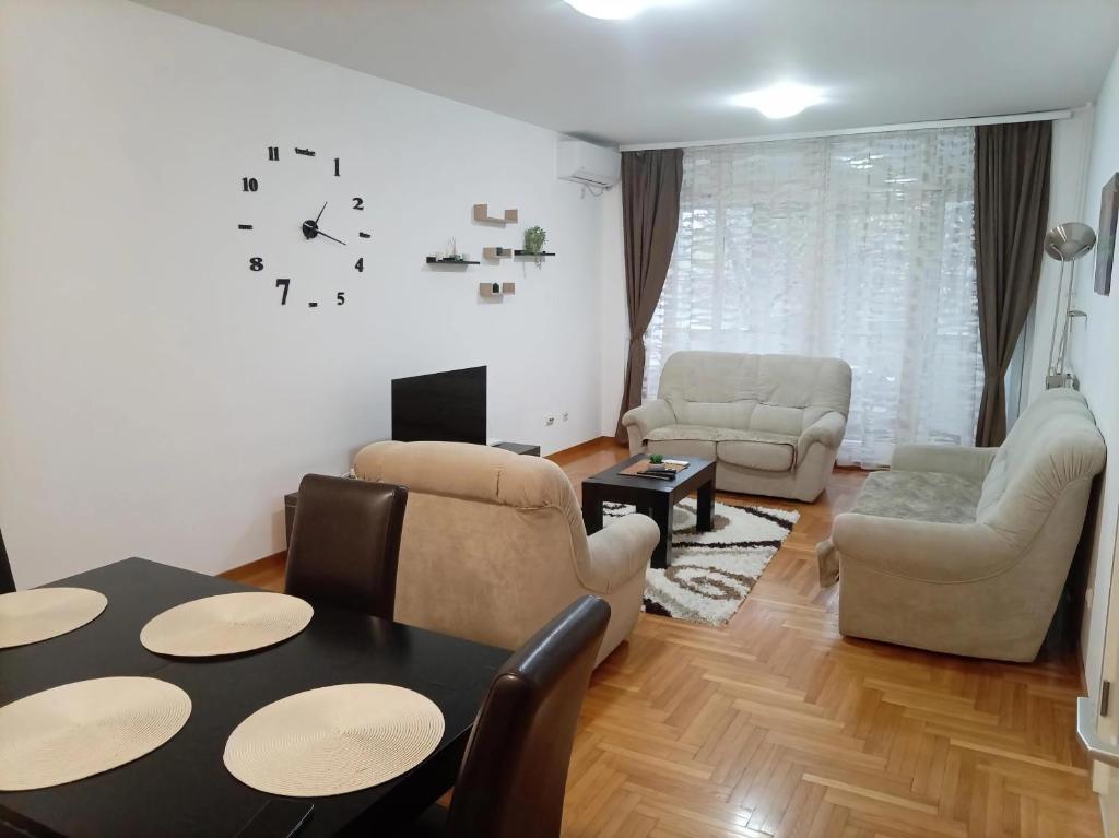 ein Wohnzimmer mit einem Tisch, Stühlen und einer Uhr in der Unterkunft Linda Apartments- Arena in Novi Beograd