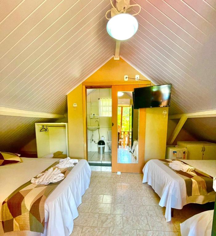 two beds in a room with a ceiling at Pousada Villa Três in Serra Negra