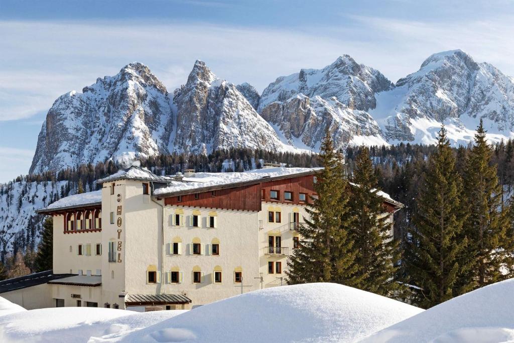 a building in front of a snow covered mountain at B&B Hotel Passo Tre Croci Cortina in Cortina dʼAmpezzo