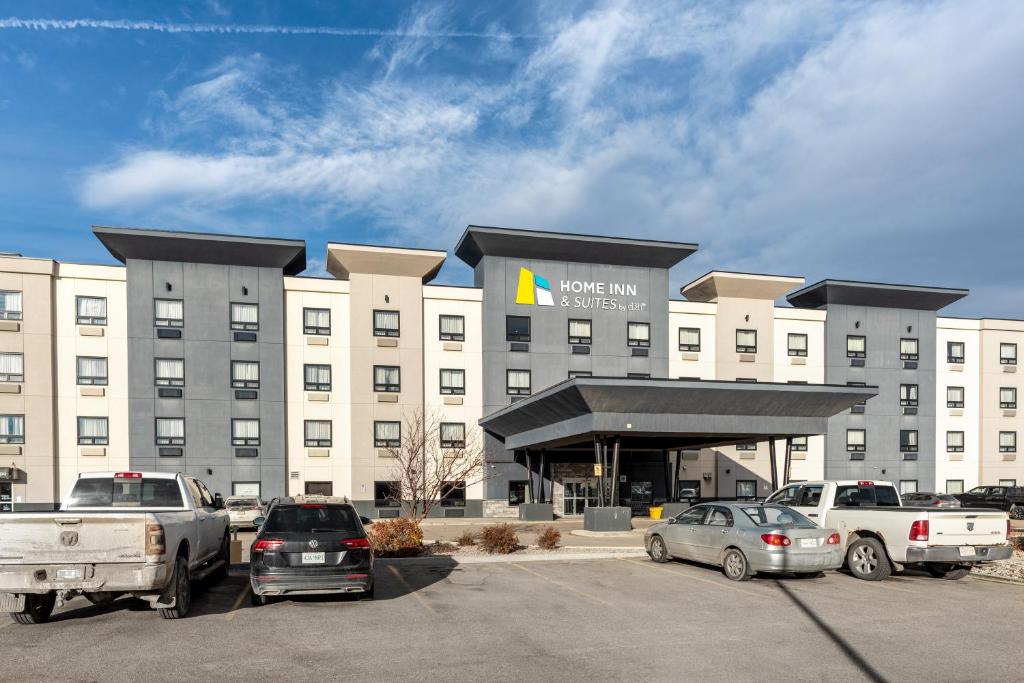 un grand hôtel avec des voitures garées dans un parking dans l'établissement Home Inn & Suites Regina Airport, à Regina