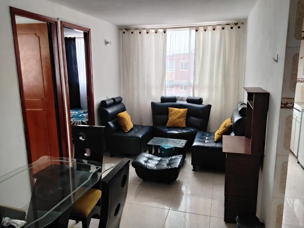 a living room with a black couch and a chair at Apartamento cerca del aeropuerto in Bogotá