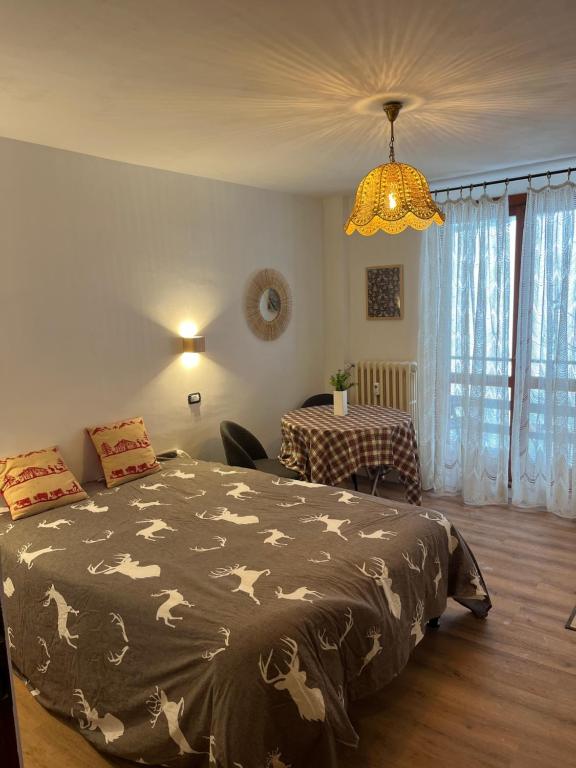 een slaapkamer met een bed, een tafel en een kroonluchter bij Appartamento Moon River Monolocale in Limone Piemonte