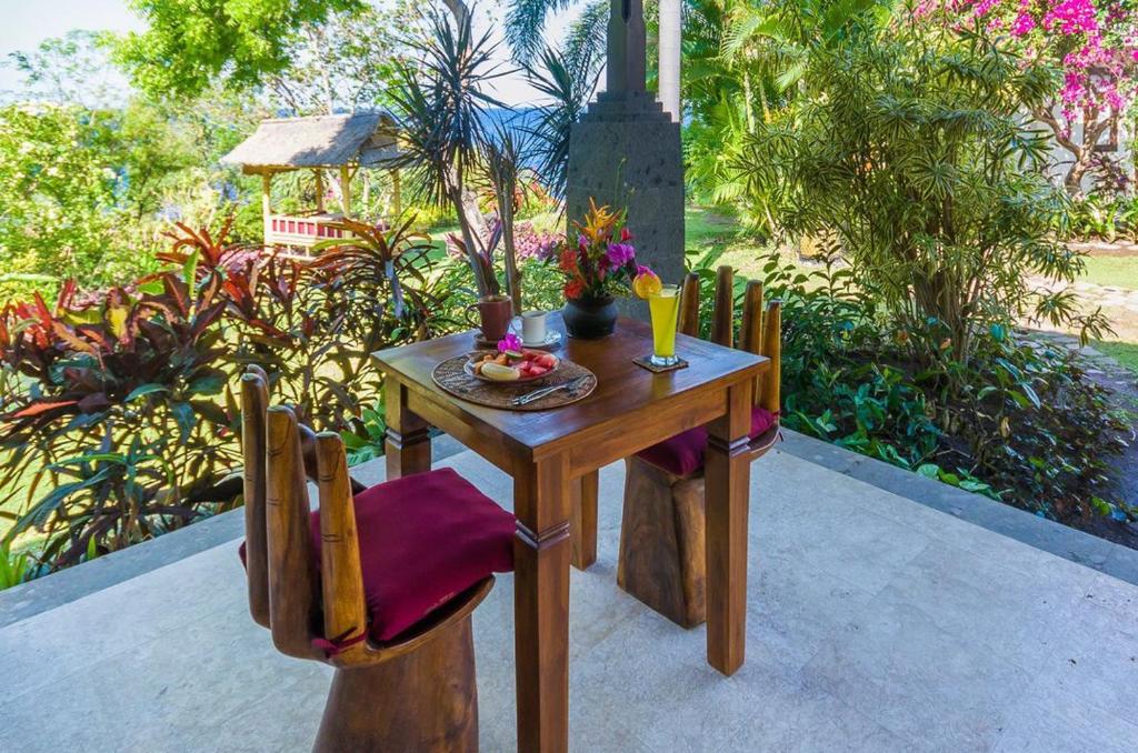 - une table et des chaises en bois avec un bol de fruits dans l'établissement Toyabali Resort, Dive & Relax, à Tulamben