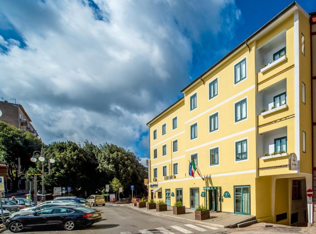 żółty budynek z samochodami zaparkowanymi na parkingu w obiekcie New Petit Hotel w mieście Tempio Pausania