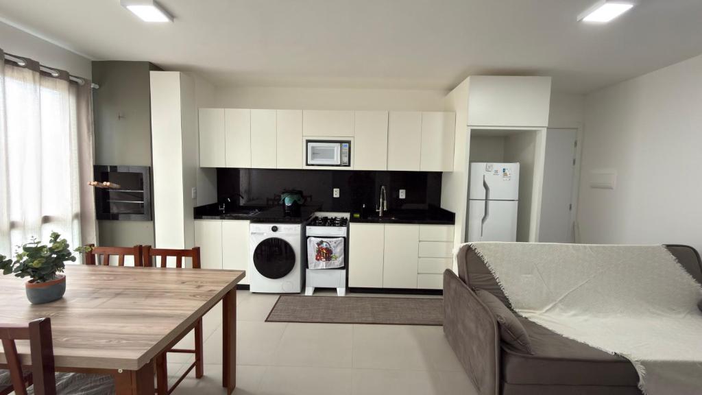 een keuken en een woonkamer met een tafel en een bed bij Apartamento Res Ilha Bella in Passo De Torres