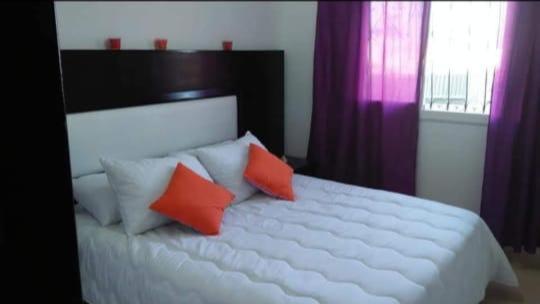 a bedroom with a large white bed with red pillows at bel appartement à Martil in Martil