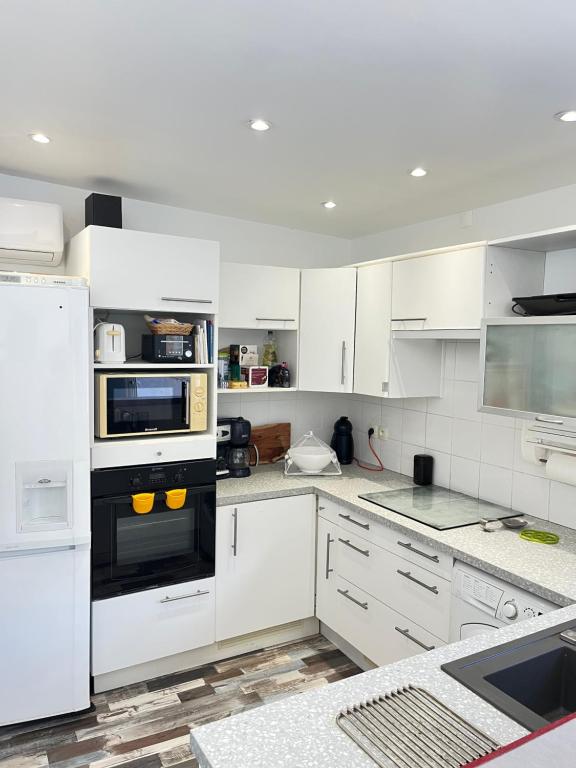 een keuken met witte kasten en een zwarte oven bij Villa Josèphe in Capbreton