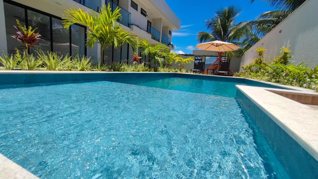 a swimming pool in front of a building with a house at Mansão dos Mares 06 in Ilhéus