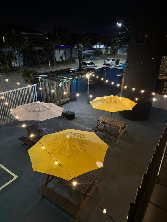 Twee gele parasols op een terras 's nachts bij Hostel Farol in Pontal do Paraná