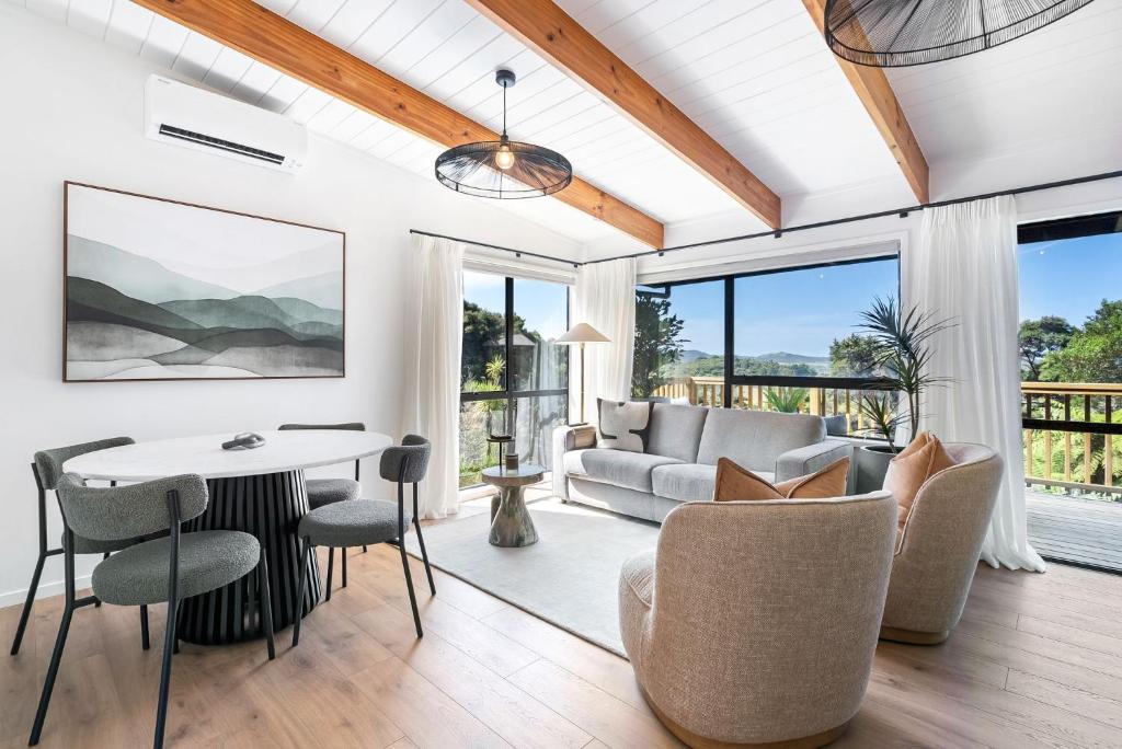 a living room with a couch and a table and chairs at Tui & Nikau Cabins in Mangawhai