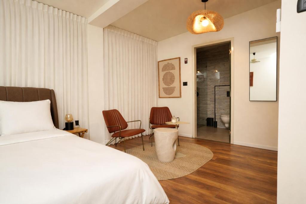 a bedroom with a bed and two chairs at One Apartments TLV in Tel Aviv