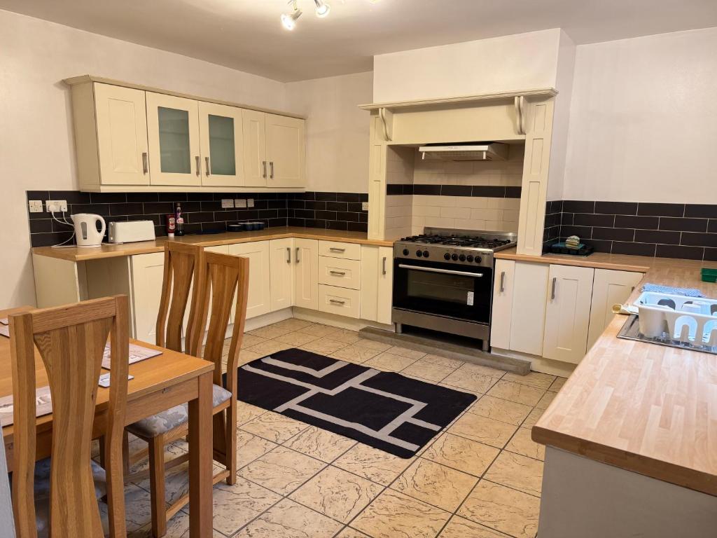 een keuken met witte kasten, een tafel en een fornuis bij Sowerby Homes in Sowerby Bridge