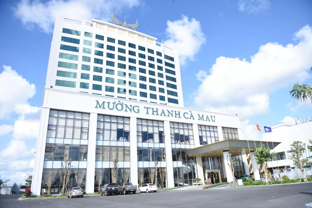 un gran edificio de oficinas con coches aparcados frente a él en Muong Thanh Luxury Ca Mau Hotel, en Cà Mau