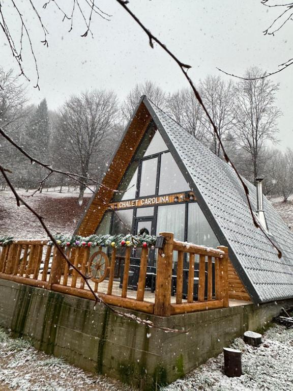 una casa con una terrazza in legno nella neve di Chalet Carolina a Padeş
