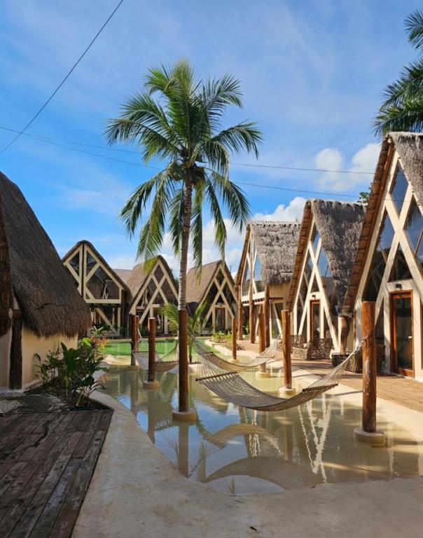 ein Ferienresort mit einer Palme und einigen Gebäuden in der Unterkunft Kaaj Ndomi in Bacalar