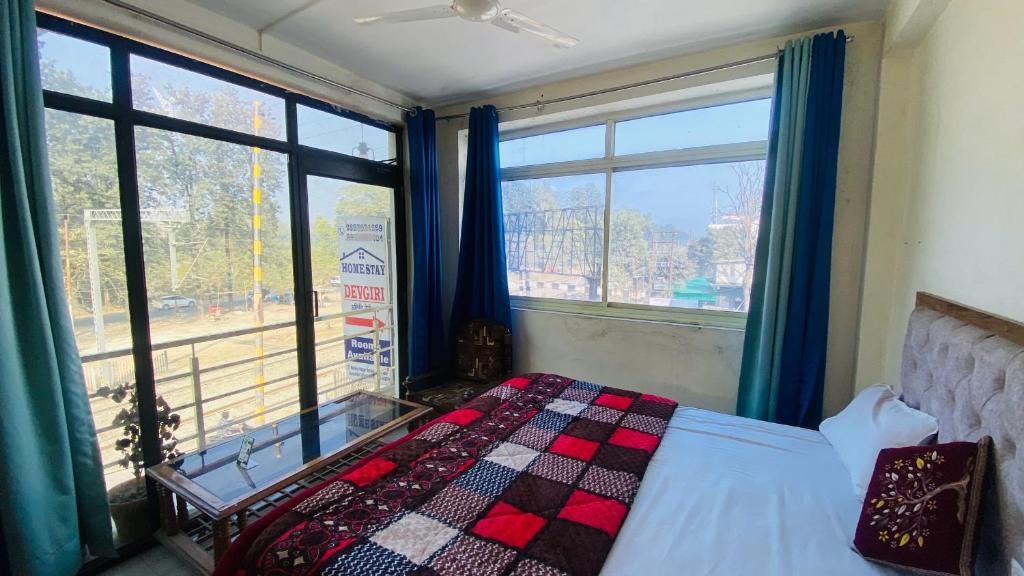 een slaapkamer met een bed en 2 grote ramen bij Homestay Devgiri by YatriMap in Rishīkesh