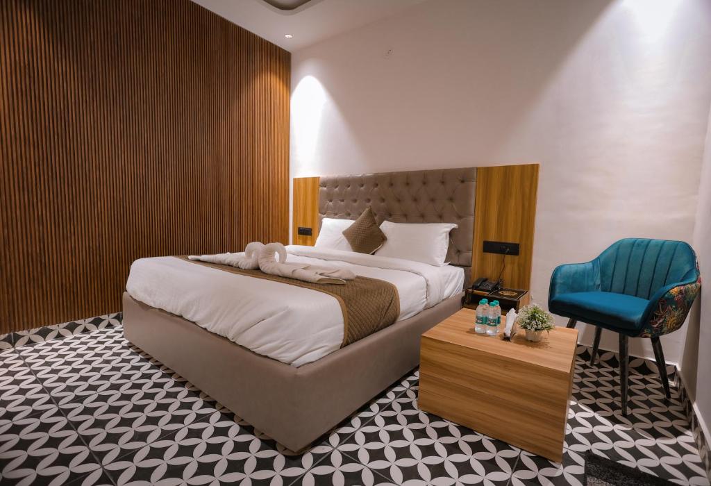 een slaapkamer met een groot bed en een blauwe stoel bij Troy Resorts and wellness in Zirakpur