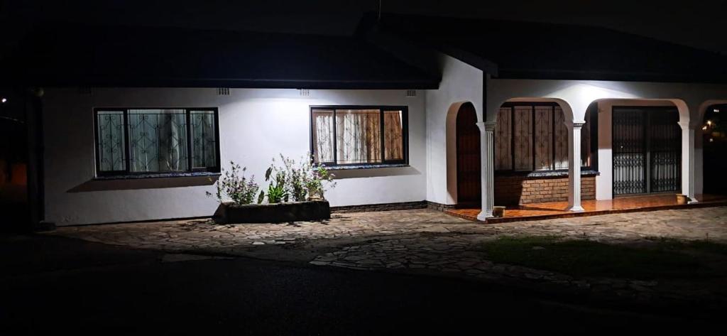 een huis met een poort en twee ramen 's nachts bij 25 Jacaranda Lodge & Backpackers in Pinetown