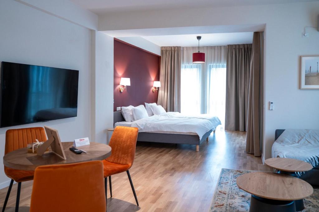 a hotel room with two beds and a table and chairs at Habitat Suites - Modern Apartments with Terraces and Free Parking in Craiova