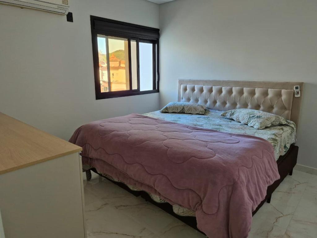 een slaapkamer met een bed met een roze deken en een raam bij Ap Novo 303! Villa Premium in Piratuba
