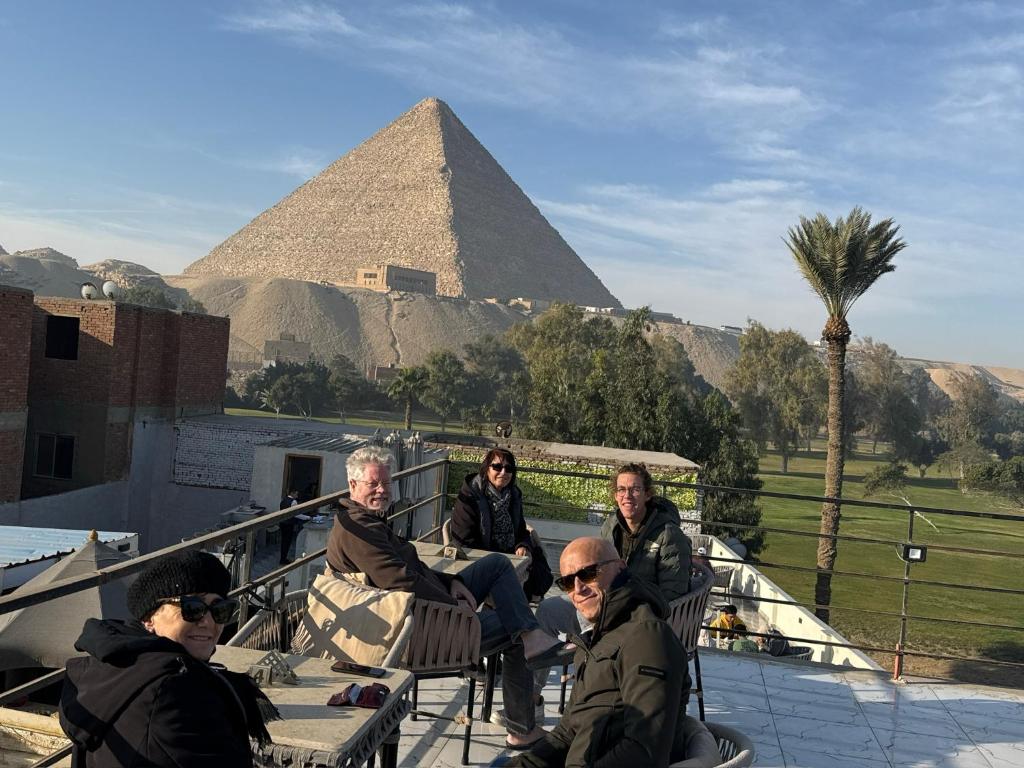 een groep mensen die voor de piramides zit bij garden pyramid view in Caïro