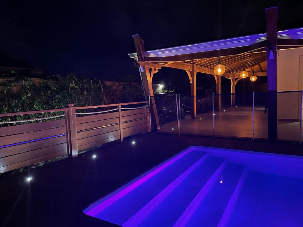 a swimming pool with purple lights on a deck at night at Villa fleurs d'Antalia in Anse-Bertrand