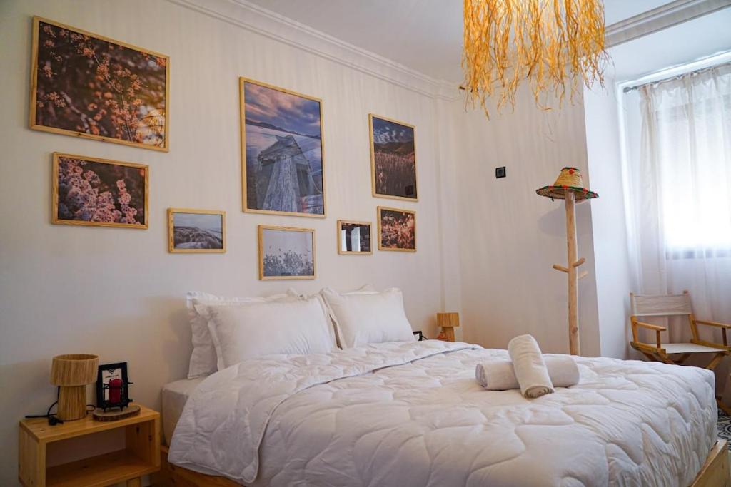 ein Schlafzimmer mit einem großen weißen Bett mit Bildern an der Wand in der Unterkunft Happiness Apartment in Ouarzazate