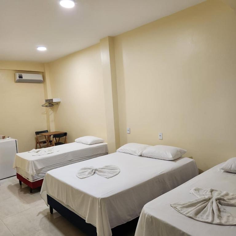 una camera con due letti con lenzuola bianche di Hotel Rocha a Barcarena