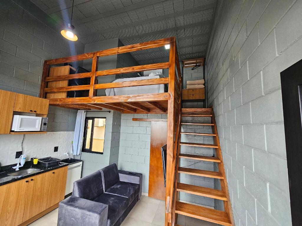 a loft bed in a small room with a couch at Residencial Zille - Lofts e Studios in São Miguel dʼOeste
