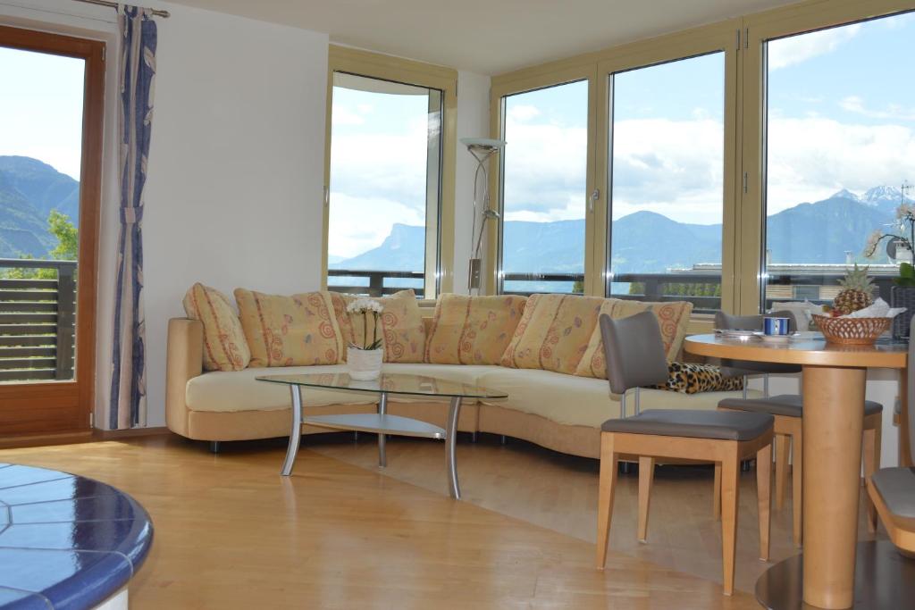 uma sala de estar com um sofá, mesas e janelas em Residence Ladurn em Tirolo