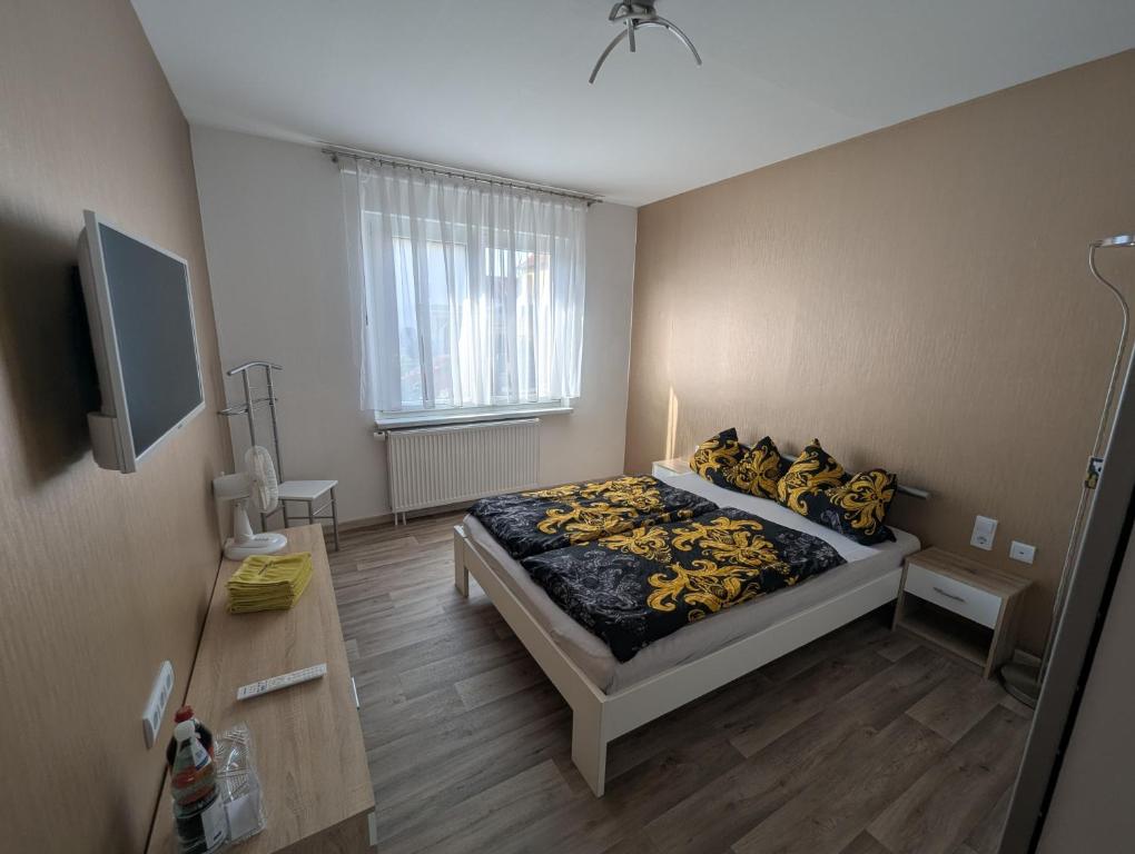 a bedroom with a bed with yellow pillows and a television at Pension zum Ringelberg in Erfurt