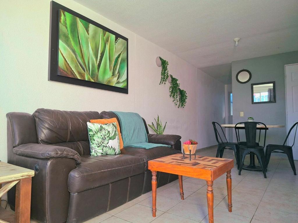 een woonkamer met een bruine leren bank en een tafel bij Casa Veta Qro in Villa del Pueblito