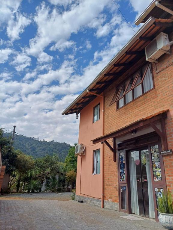 a brick building with a blue sky and clouds at Hostel Dina & Suítes in Pomerode