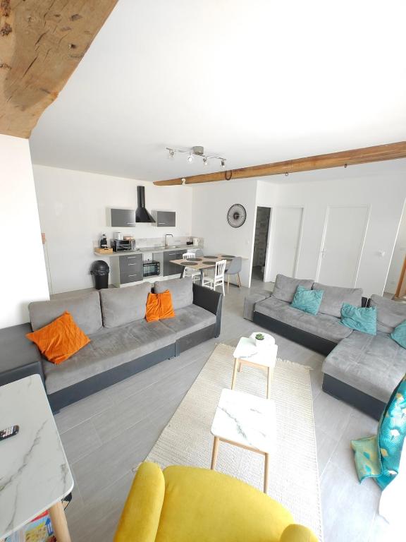 a living room with two couches and a table at Le Grand Mauperthuis F4 in Forges