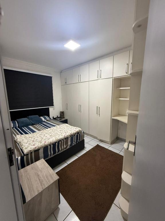 een slaapkamer met een bed en witte kasten bij Apartamento inteiro 45m, centro, com garagem in Torres